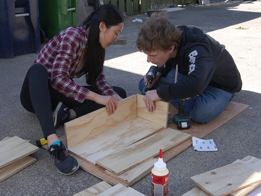 Holding up the front and side panels to form the first corner.